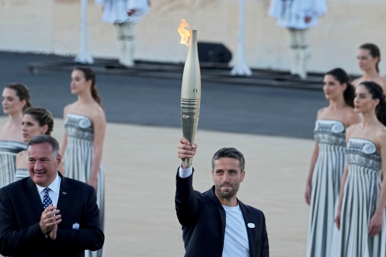 Tony Estanguet, presidente de París 2024, a la derecha, sostiene la llama olímpica mientras Spyros Capralos, jefe del Comité Olímpico de Grecia, a la izquierda, aplaude durante la ceremonia de entrega de la llama en el estadio Panatenaico, donde se celebraron los primeros juegos modernos en 1896, en Atenas, el viernes. , 26 de abril de 2024.