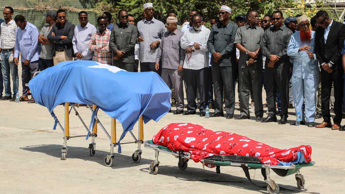Los líderes políticos oran frente a los dos cuerpos de los legisladores locales, incluida Amina Mohamed Abdi, después de ser trasladados en avión desde Beledweyne, en el Aeropuerto Internacional Aden Adde en Mogadiscio, Somalia, el 24 de marzo de 2022. - El número de muertos por ataques gemelos en el centro de Somalia el 24 de marzo de 2022. La noche del 23 de marzo de 2022 superó los 30, dijo a la AFP el jefe de policía del distrito de Beledweyne el 24 de marzo de 2022, y el grupo insurgente Al-Shabaab dijo que estaba atacando a los políticos antes de las elecciones. (Foto de Hassan Ali ELMI / AFP)
