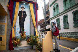 Una mujer reza cerca de un cuadro con la imagen de José Gregorio Hernández en la calle donde murió en un accidente automovilístico en 1919, en el barrio La Pastora de Caracas, Venezuela, el 28 de abril de 2021. Conocido como el "médico de los pobres Hernández será beatificado el 30 de abril por la Iglesia Católica, un paso hacia su santidad. (Foto AP / Ariana Cubillos)