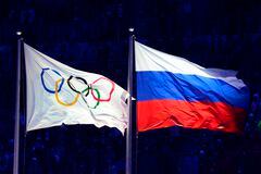 Esta fotografía tomada el 7 de febrero de 2014 muestra una bandera rusa (derecha) y una bandera olímpica izada durante la ceremonia de apertura de los Juegos Olímpicos de Invierno de Sochi en el Estadio Olímpico Fisht en Sochi.