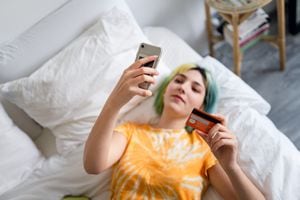 Mujer joven con cabello teñido está comprando en línea con una tarjeta de crédito. Foto: Getty Images
