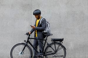 Joven parado por bicicleta eléctrica con smartphone