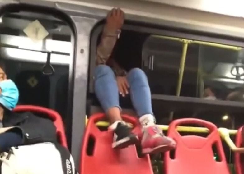 Mujer se baja por la ventana de un bus de TransMilenio.