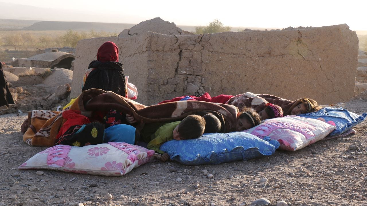 Niños afganos descansan bajo una manta junto a casas dañadas tras el terremoto en la aldea de Sarbuland del distrito de Zendeh Jan de la provincia de Herat el 7 de octubre de 2023 (Foto de Mohsen KARIMI / AFP)