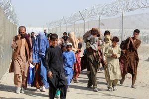 Afghan people walk inside a fenced corridor as they enter Pakistan at the Pakistan-Afghanistan border crossing point in Chaman on August 25, 2021 following the Taliban's stunning military takeover of Afghanistan. (Photo by - / AFP)