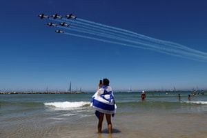 Una persona con la bandera de Israel fotografía un vuelo que forma parte de un espectáculo aéreo organizado para las celebraciones del 75º día de la Independencia de Israel, en Tel Aviv, Israel, el 26 de abril de 2023. 