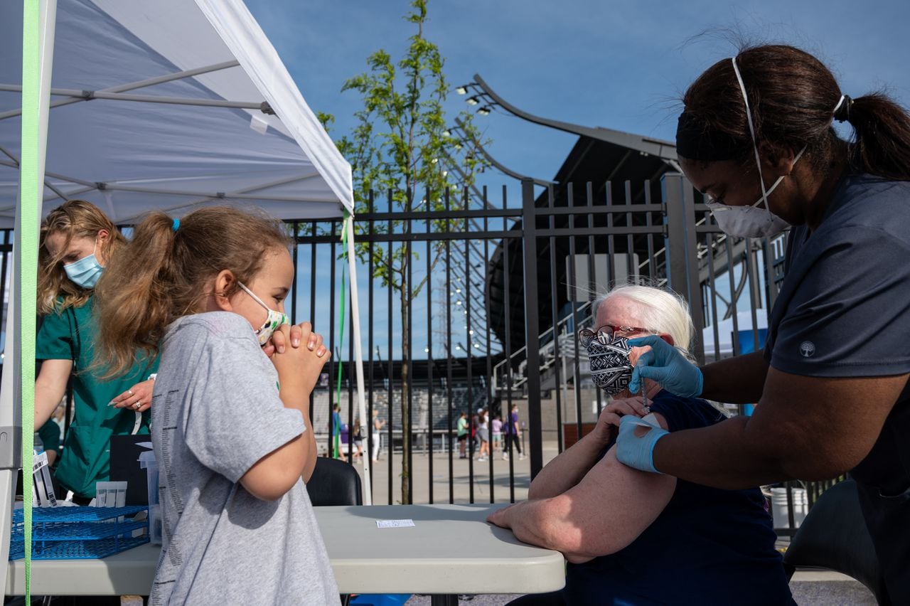 Una niña hace una mueca mientras que se abuela recibe la vacuna de Pfizer contra el covid-19 durante un evento de vacunación en Louisville, Kentucky, 26 de abril 2021