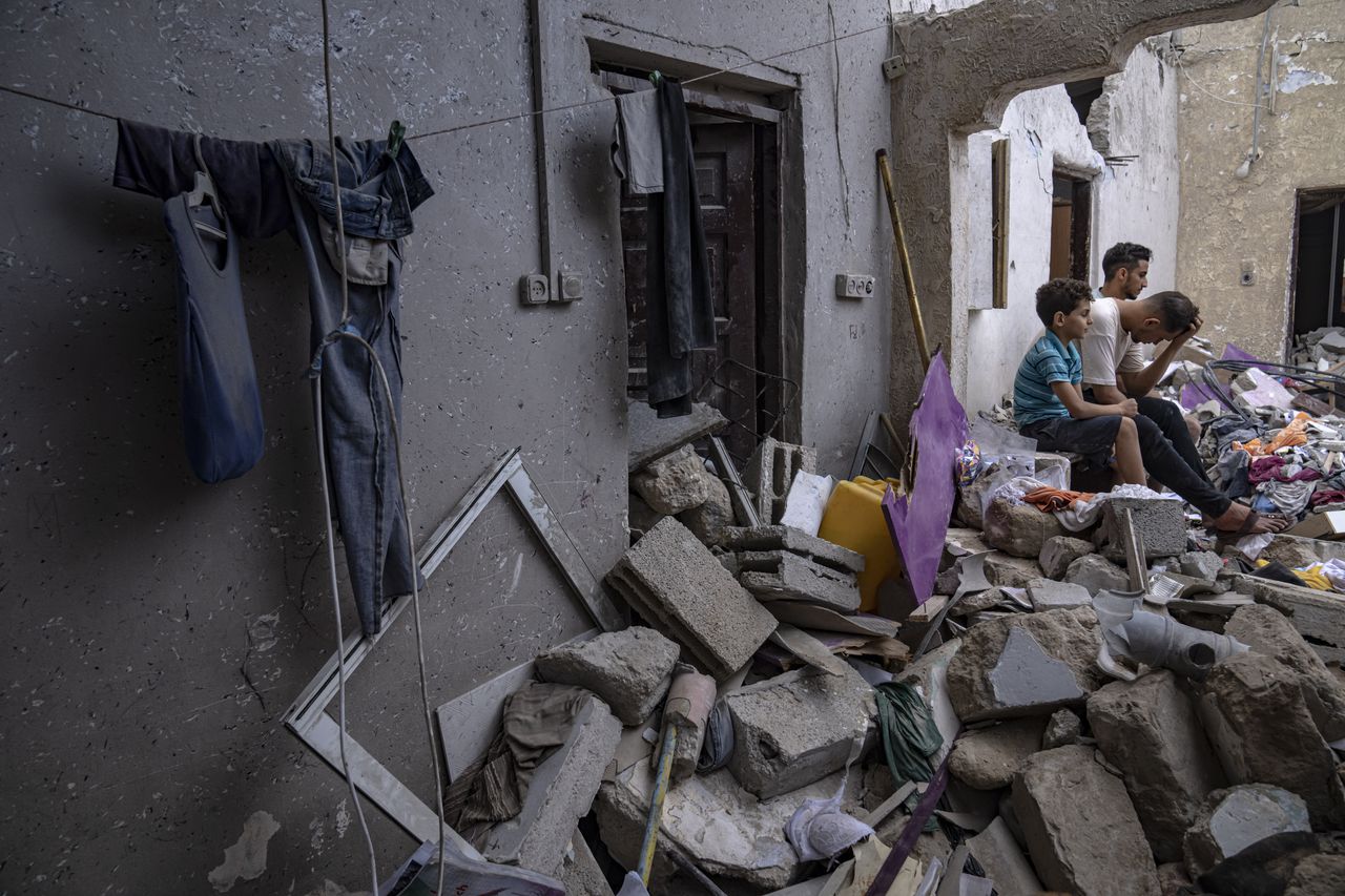 Palestinos sentados entre los escombros de una casa después de que fuera alcanzada por un bombardeo israelí en Khan Younis, en el sur de la Franja de Gaza, el domingo 29 de octubre de 2023. (AP Foto/Fatima Shbair)