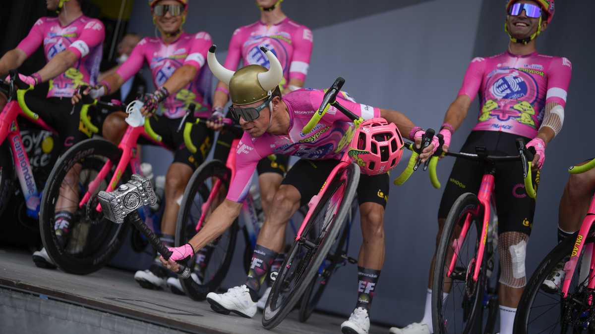 Colombia's Rigoberto Uran jokes on the podium with a Viking helmet and a hammer, as his Education First EasyPost teammates line up prior to the third stage of the Tour de France cycling race over 182 kilometers (113 miles) with start in Vejle and finish in Sonderborg, Denmark, Sunday, July 3, 2022. (AP Photo/Thibault Camus)