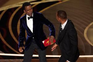 El presentador Chris Rock, a la izquierda, reacciona tras ser confrontado por Will Smith mientras presentaba el premio al mejor documental en la ceremonia de los Oscar, tras hacer un chiste sobre su esposa, Jada Pinkett Smith, el domingo 27 de marzo de 2022 en el Teatro Dolby en Los Ángeles. (Foto AP/Chris Pizzello)