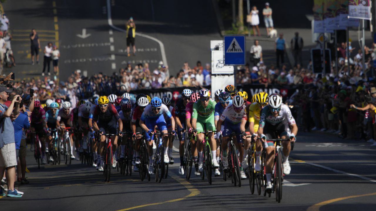 The pack with stage winner Belgium's Wout Van Aert, wearing the best sprinter's green jersey, climbs towards the finish line during the eighth stage of the Tour de France cycling race over 186.5 kilometers (115.9 miles) with start in Dole, France, and finish in Lausanne, Switzerland, Saturday, July 9, 2022. (AP/Daniel Cole)