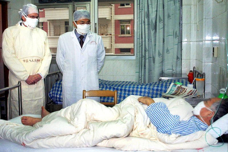Robert Maguire de la OMS y un médico chino visitan a un paciente con SARS en Guangzhou, China – abril de 2003.