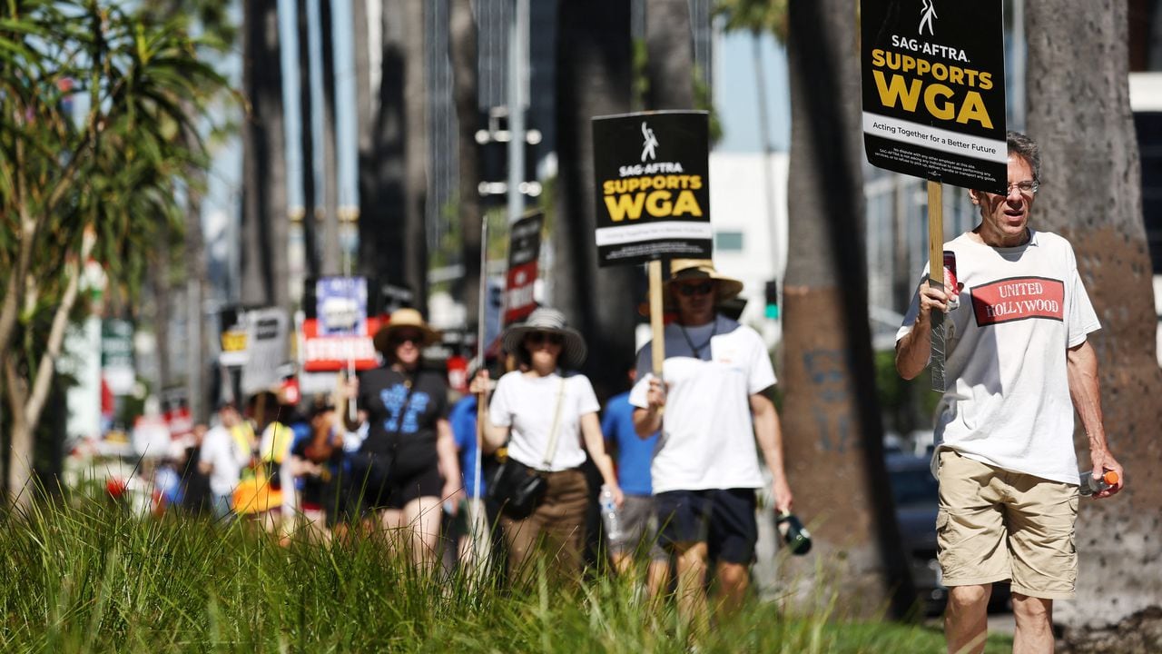LOS ANGELES, CALIFORNIA - JULY 13: A sign reads 'SAG-AFTRA Supports WGA' as SAG-AFTRA members walk the picket line in solidarity with striking WGA (Writers Guild of America) workers outside Netflix offices on July 13, 2023 in Los Angeles, California. Members of SAG-AFTRA, Hollywood�s largest union which represents actors and other media professionals, will join striking WGA (Writers Guild of America) workers at midnight in the first joint walkout against the studios since 1960. The strike could shut down Hollywood productions completely with writers in the third month of their strike against the Hollywood studios.   Mario Tama/Getty Images/AFP (Photo by MARIO TAMA / GETTY IMAGES NORTH AMERICA / Getty Images via AFP)