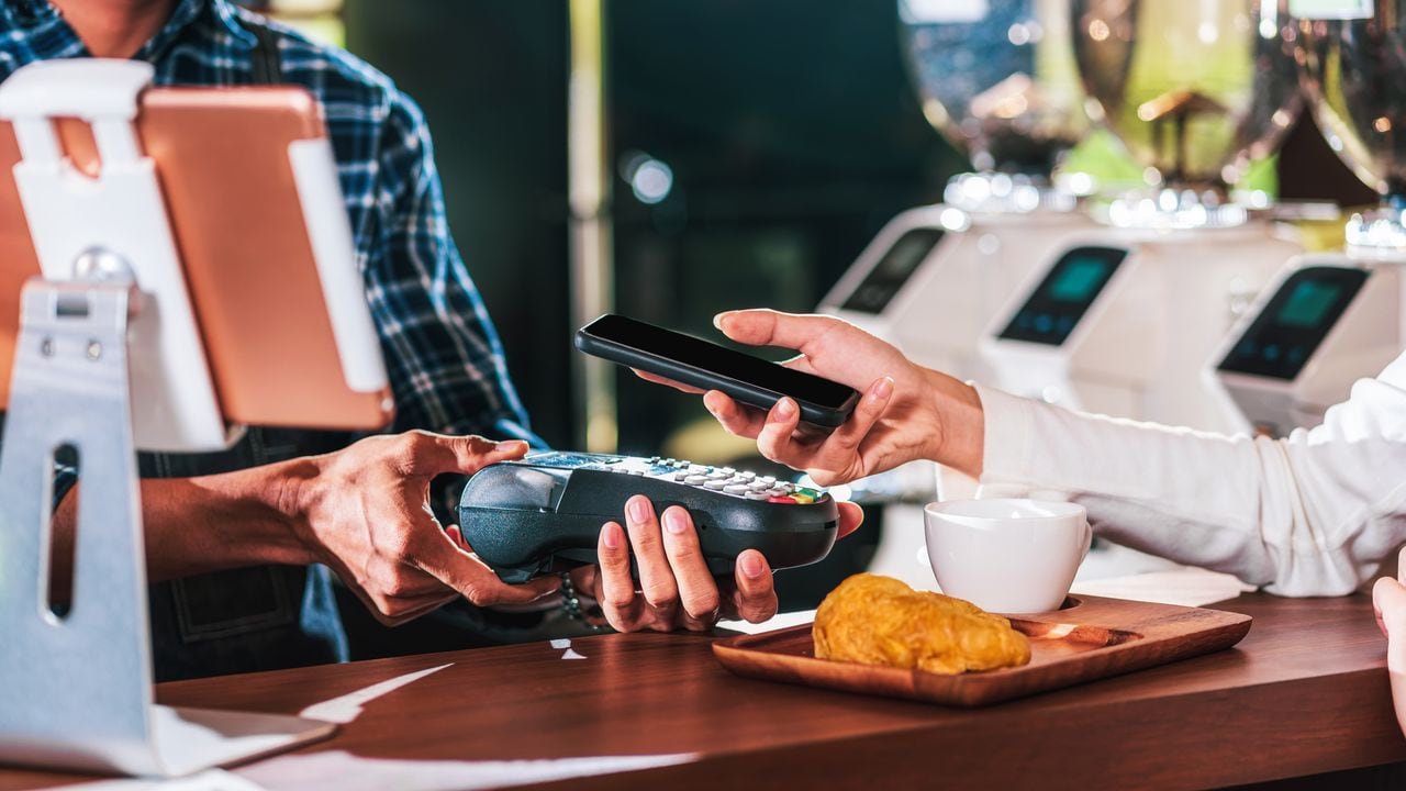 Propietario de una pequeña empresa y puesta en marcha en una cafetería, Primer cliente asiático mano del hombre pagando dinero a través del canal sin contacto mediante la aplicación de banca móvil al propietario de una pequeña empresa en la mesa de la cafetería