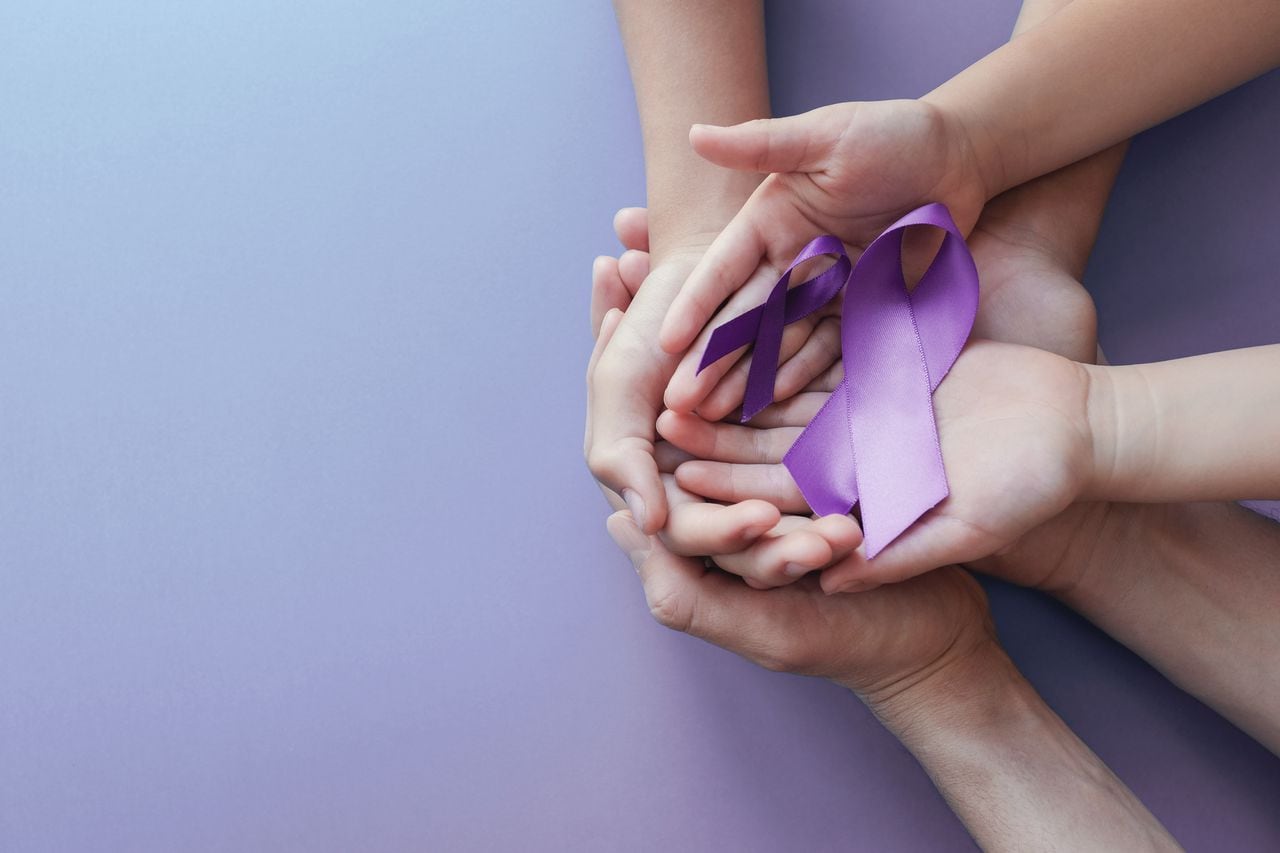 Manos de adultos y niños sosteniendo cintas moradas, enfermedad de Alzheimer, cáncer de páncreas, conciencia de la epilepsia, día mundial del cáncer sobre fondo púrpura