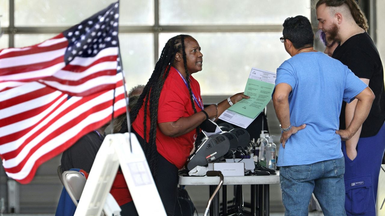 Un funcionario electoral entrega a los votantes boletas con instrucciones sobre cómo votar durante la votación para las elecciones intermedias en un colegio electoral en Kissimmee, Florida, el 8 de noviembre de 2022. (Foto de Gregg Newton / AFP)