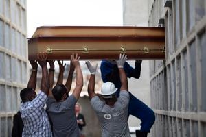 Los restos de una mujer que murió por complicaciones relacionadas con el COVID-19 son colocados en un nicho por trabajadores del cementerio y familiares en el cementerio de Inahuma en Río de Janeiro, Brasil, el martes 13 de abril de 2021. (Foto AP / Silvia Izquierdo)