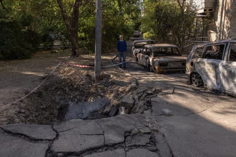 Un hombre mira un cráter junto a autos quemados en el sitio donde cayeron los escombros de drones interceptados por Rusia, el 31 de mayo de 2023 en Kiev, Ucrania.