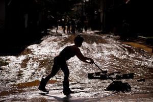 BELO HORIZONTE, BRAZIL - JANUARY 12: A woman removes the mud from the street caused by the overflow of the Rio das Velhas river on January 12, 2022 in Honorio Bicalho, Brazil. Heavy rains over the weekend caused landslides and floods in the Minas Gerais region. A maximum alert was issued due to the risk of the Carioca dam in Para de Minas bursting as a result of intense rains. According to authorities 10 people died between sunday and monday and the number of affected population is over 17 thousand people. (Photo by Pedro Vilela/Getty Images)