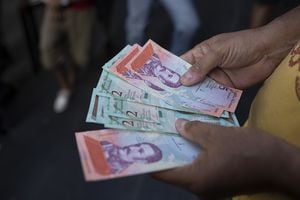A man displays new 5 and 2 sovereign bolivar banknotes for a photograph after withdrawing them from an automated teller machine (ATM) in Caracas, Venezuela, on Monday, Aug. 20, 2018. The Venezuelan government is re-denominating the bolivar currency by lopping off five zeroes, this as it carried out one of the greatest currency devaluations in history over the weekend. Photographer: Carlos Becerra/Bloomberg via Getty Images
