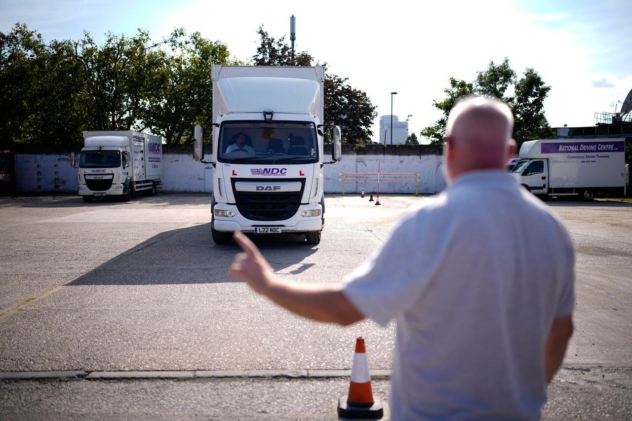 El instructor Graham Bolger da indicaciones a un estudiante que aprende a menejar camiones en el National Driving Centre de Croydon, al sur de Londres, el 22 de septiembre del 2021. Una escasez de camioneros está generando escasez en otros sectores en Gran Bretaña, ya que no hay quién transporte las mercancías. (AP Photo/Matt Dunham)