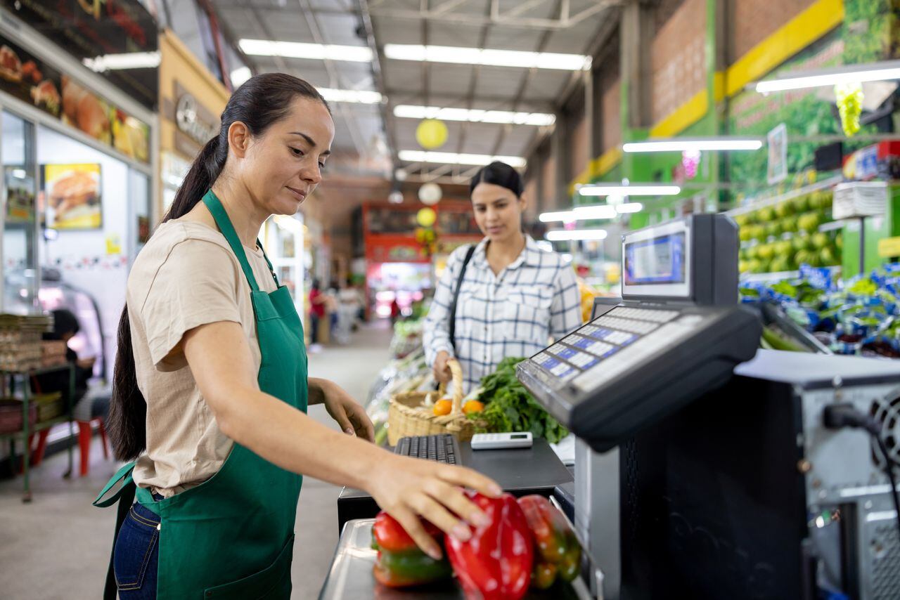 Latin American female cashier registering products while working at the supermarket