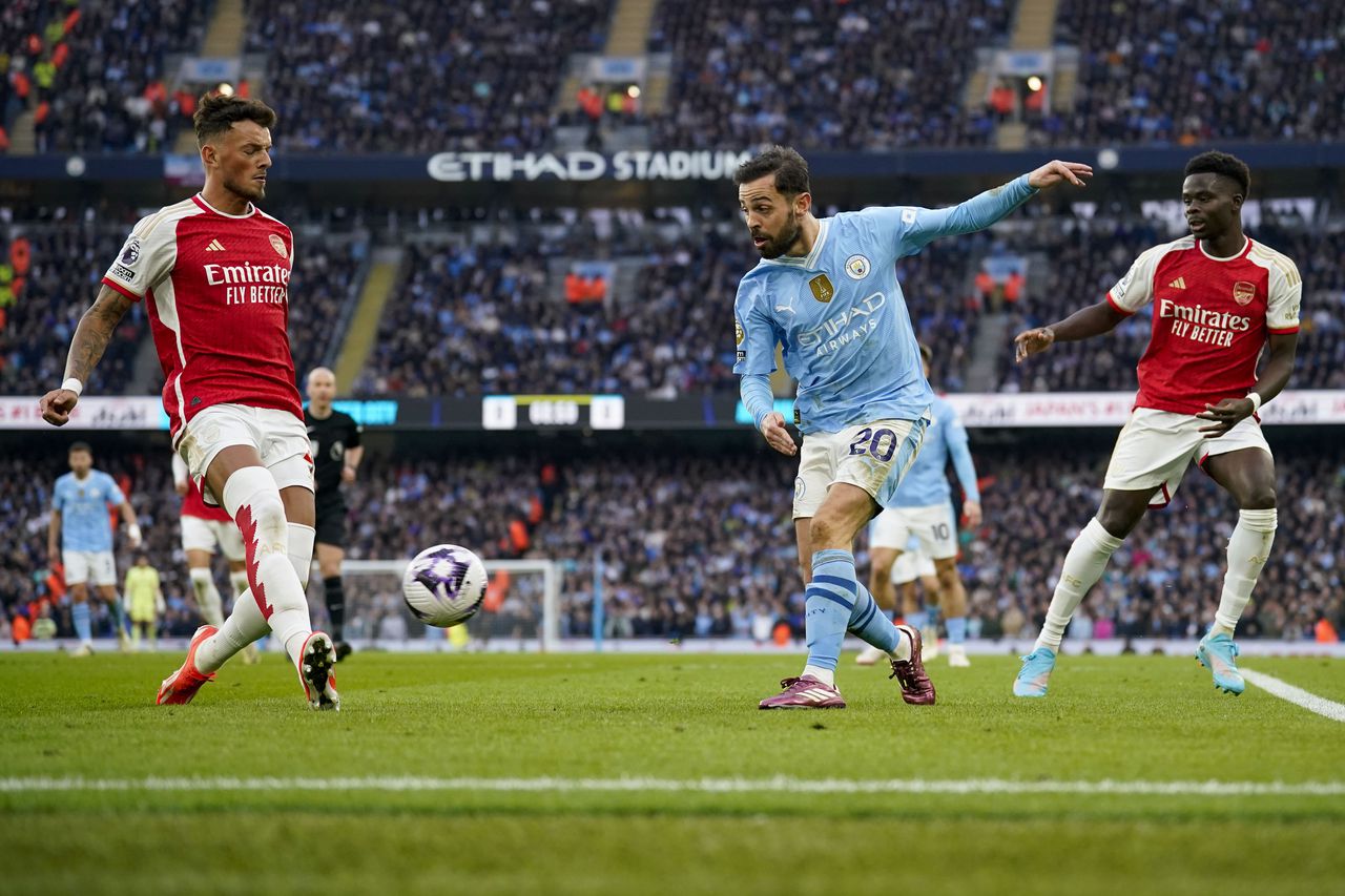 Arsenal's Ben White, left, tries to block a shot from Manchester City's Bernardo Silva during the English Premier League soccer match between Manchester City and Arsenal at the Etihad stadium in Manchester, England, Sunday, March 31, 2024. (AP Photo/Dave Thompson