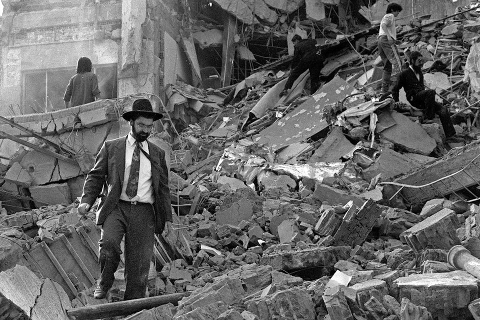 (ARCHIVOS) En esta foto de archivo tomada el 18 de julio de 1994, un hombre camina sobre los escombros que quedaron después de que una bomba explotó en la Asociación Mutual Israelí Argentina (AMIA) en Buenos Aires. - Pasaron veinticinco años de la explosión en la sede del centro judío AMIA, que causó 85 muertos en el atentado más grave de la historia argentina que continúa impune hasta el día de hoy. (Foto de ALI BURAFI / AFP)