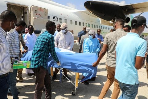 La gente descarga el cuerpo de la legisladora local después de que muriera en un atentado suicida con bomba en Beledweyne, en el Aeropuerto Internacional Aden Adde en Mogadishu, Somalia, el 24 de marzo de 2022. - El número de muertos por ataques gemelos en el centro de Somalia el 23 de marzo, La noche de 2022 superó los 30, dijo a la AFP el jefe de policía del distrito de Beledweyne el 24 de marzo de 2022, y el grupo insurgente Al-Shabaab dijo que estaba atacando a los políticos antes de las elecciones. (Foto de Hassan Ali ELMI / AFP)