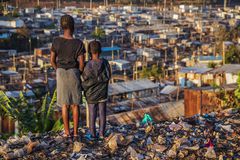 Niñas africanas de pie en la basura y mirando casas en el barrio marginal de Kibera, Kenia, África Oriental. Kibera es el barrio marginal más grande de Nairobi, el barrio marginal urbano más grande de África y el tercero más grande del mundo