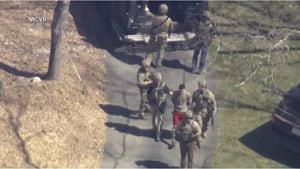 Esta imagen tomada de un video proporcionado por WCVB-TV muestra a Jack Teixeira, en camiseta y pantalones cortos, siendo detenido por agentes tácticos armados el jueves 13 de abril de 2023 en Dighton, Massachusetts.