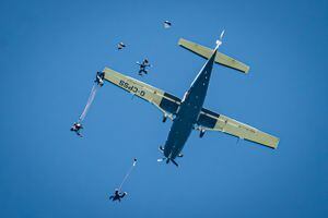 Los paracaídas se despliegan después de la caída libre debajo de un avión Cessna