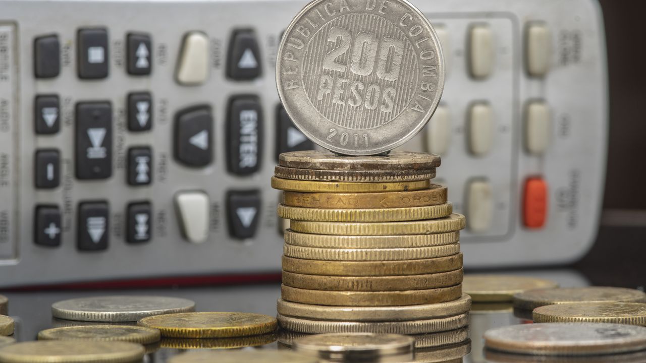 Pile and coins of Two Hundred Colombian Pesos with a calculator as a background. Income, expenses, taxes, financial data