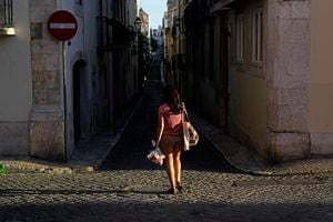 Una mujer camina por una calle mientras se pone el sol en Lisboa. (Foto AP / Armando Franca)