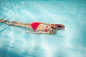 Mujer nadando bajo el agua en la piscina al aire libre