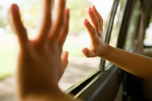 Child's hands touching car window