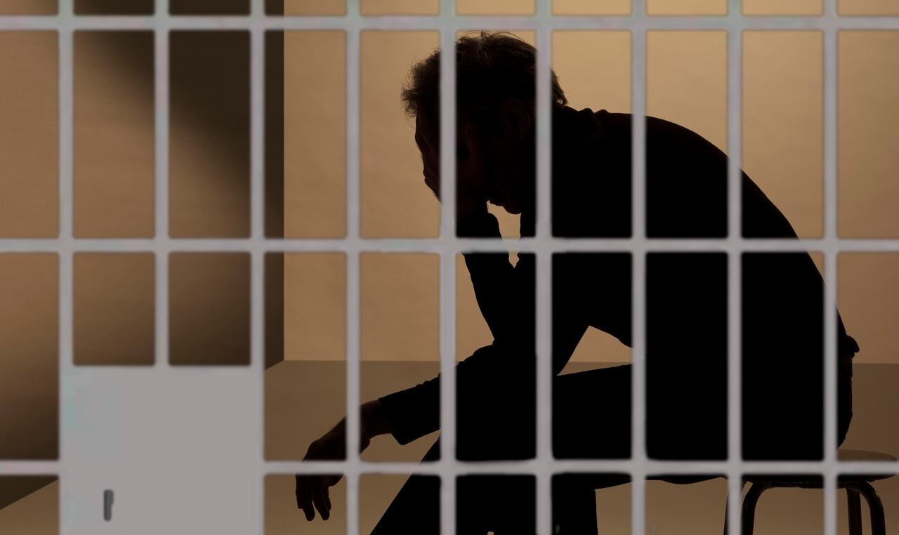preso en prisión, silueta más allá de los barrotes de la celda