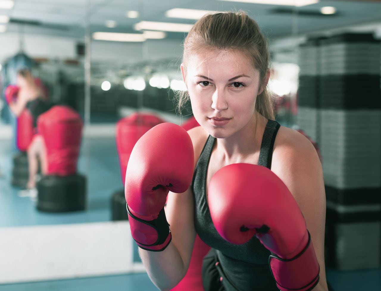 Retrato de mujer griega positiva que está entrenando en box gym.