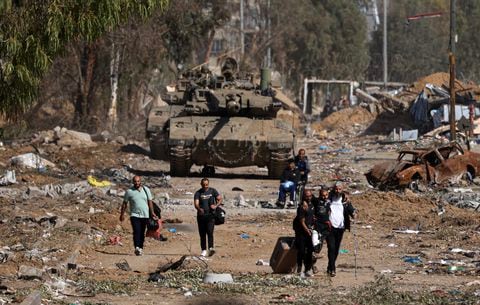 Palestinos que huyen del norte por la carretera de Salaheddine pasan junto a un tanque del ejército israelí en el distrito de Zeitoun, en las afueras del sur de la ciudad de Gaza, el 24 de noviembre de 2023, tras un alto el fuego de cuatro días que comenzó a primera hora de la mañana.
