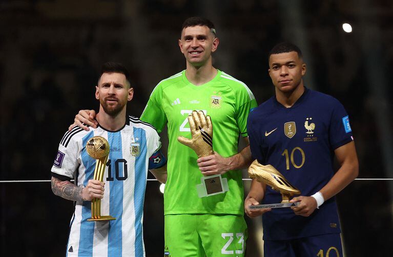 Lionel Messi, ganador del Balón de Oro, Emiliano Martínez, de Argentina, ganador del Guante de Oro, y Kylian Mbappe, de Francia, ganador del Balón de Oro, posan con los trofeos.