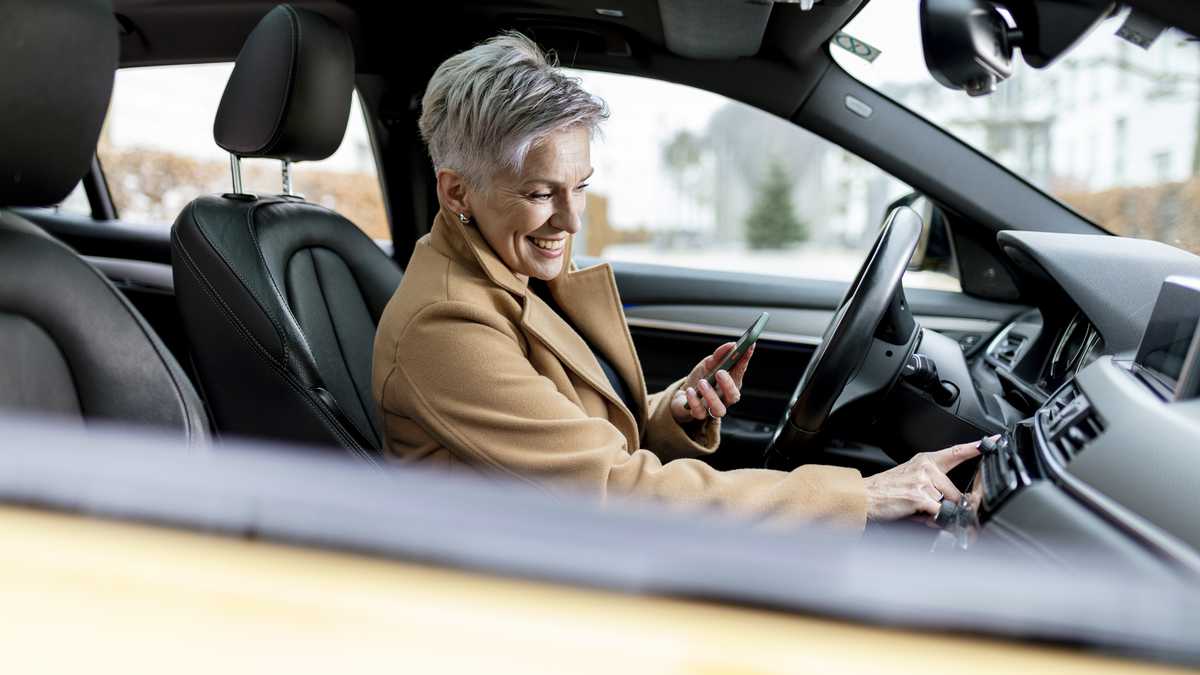 active bestager women is using smart phone to start a sharing car