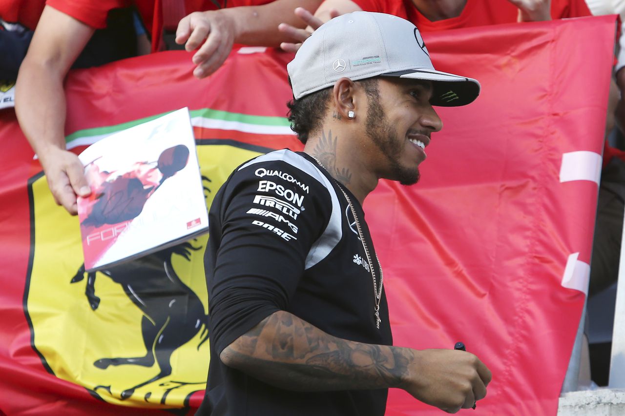 FILE - Mercedes driver Lewis Hamilton of Britain walks past Ferrari fans during a fan meeting at the Suzuka Circuit in Suzuka, central Japan, Oct. 6, 2016. Seven-time Formula One champion Lewis Hamilton has been linked with a shock move from Mercedes to Ferrari next year. (AP Photo/Toru Takahashi, File)