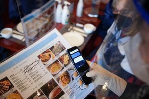 Un servidor chino usa un dispositivo de traducción para comunicarse con un invitado extranjero en el restaurante Green Dragon dentro del circuito cerrado de los Juegos Olímpicos en Zhangjiakou. Foto REUTERS/Yiming Woo