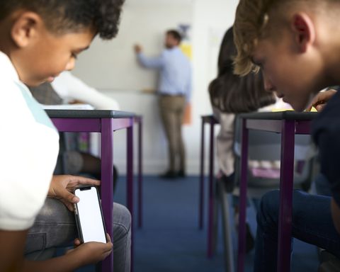 Jovenes revisan su celular en una aula de clase. Imagen de referencia