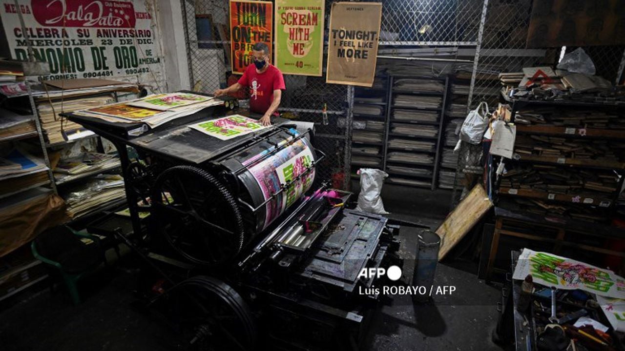 Olmedo Franco, 62, prints posters in a 1890 New York�s Reliance printing press, inside the La Linterna printing house in Cali, Colombia, on March 2, 2021. - In the heart of the colonial district of Cali, the La Linterna printing house was slowly dying out until graphic designers and street artists rekindled this beacon of traditional typography. (Photo by Luis ROBAYO / AFP)
