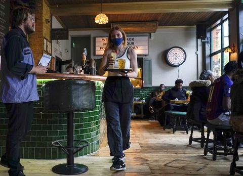 Una mesera sostiene una bandeja con bebidas en el pub Prince of Peckham, mientras reabre a los clientes interiores. (AP). Foto / Alberto Pezzali, ARCHIVO)