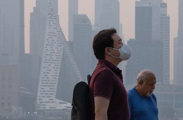 Un hombre usa una máscara facial mientras el humo continúa cubriendo el sol a medida que se eleva detrás del horizonte de Manhattan en la ciudad de Nueva York el 7 de junio de 2023, visto desde Weehawken, Nueva Jersey. (Foto de Kena Betancur/VIEWpress/Getty Images)