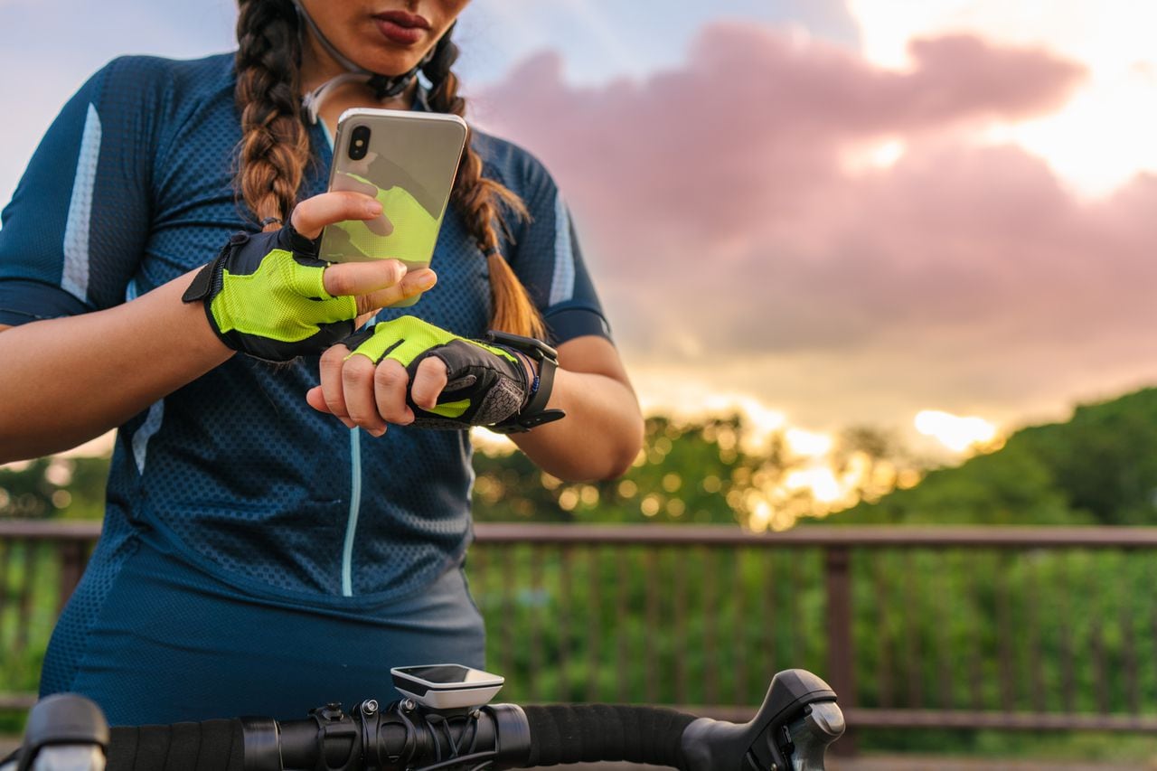 Una ciclista está configurando su reloj inteligente y su teléfono inteligente antes de andar en bicicleta.