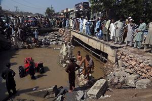 Algunas personas se paran alrededor de una carretera arrasada después de las fuertes lluvias en Charsadda, Pakistán, el martes 30 de agosto de 2022. Funcionarios de desastres dicen que casi medio millón de personas en Pakistán se hacinan en campamentos después de perder sus hogares en inundaciones generalizadas causadas por lluvias monzónicas sin precedentes en semanas recientes. Foto AP/Mohammad Sajjad