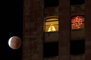 La sombra de la tierra cubre la luna llena durante un eclipse lunar parcial cuando se pone más allá de un edificio de apartamentos, el viernes 19 de noviembre de 2021, en el centro de Kansas City, Missouri Foto AP / Charlie Riedel